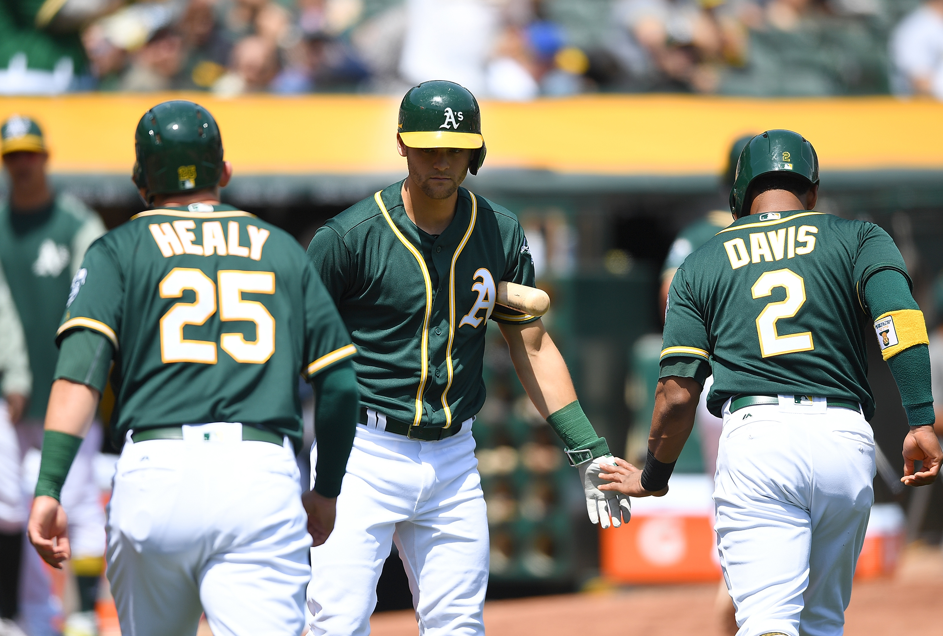 OAKLAND, CA - APRIL 19: Khris Davis #2 and Ryon Healy #25 of the Oakland Athletics are congratulated by Chad Pinder #18 after Davis and Healy both scored against the Texas Rangers in the bottom of the first inning at Oakland Alameda Coliseum on April 19, 2017 in Oakland, California. 