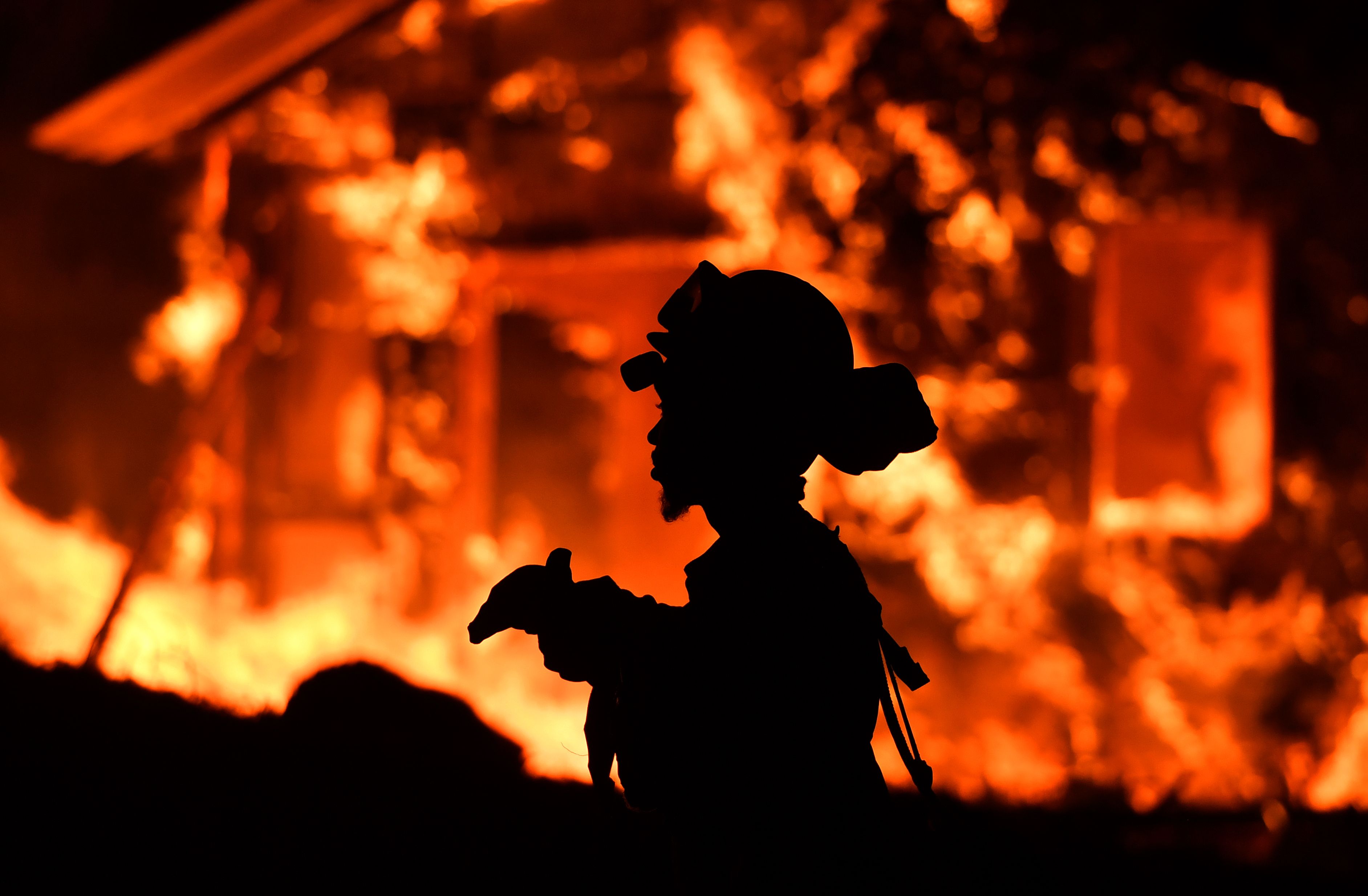 TOPSHOT - An inmate firefighter monitors flames as a house burns in the Napa wine region in California on October 9, 2017, as multiple wind-driven fires continue to whip through the region. (Credit: JOSH EDELSON/AFP/Getty Images)